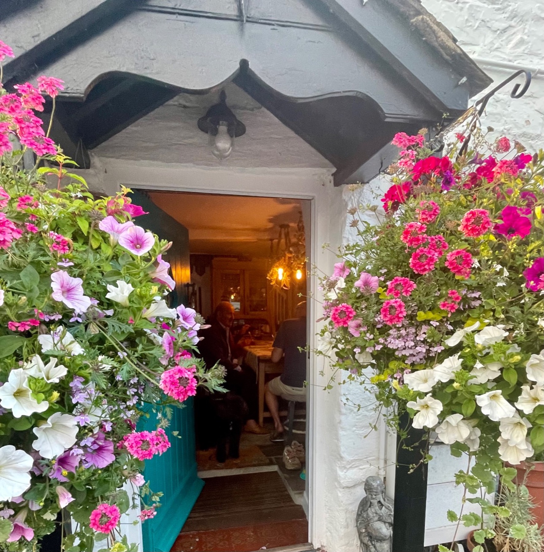 The blue cottage door open to a warmly lit dinner table inside.