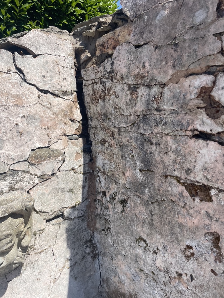 Corner of an old stone and slate wall showing cracked cement repair.
