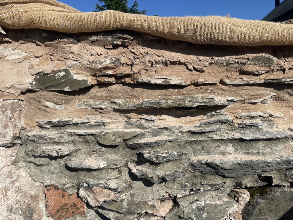 Close-up of slate layers and repair mortar under hessian.