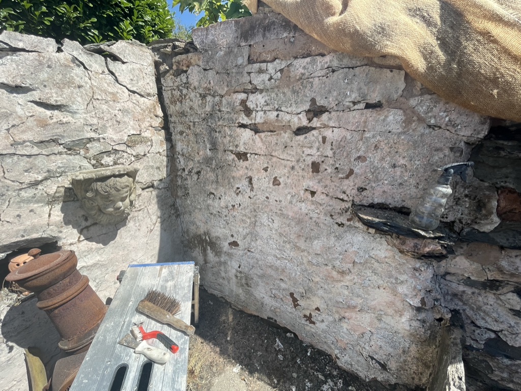 Old garden wall with tools on a work platform and hessian over the top.