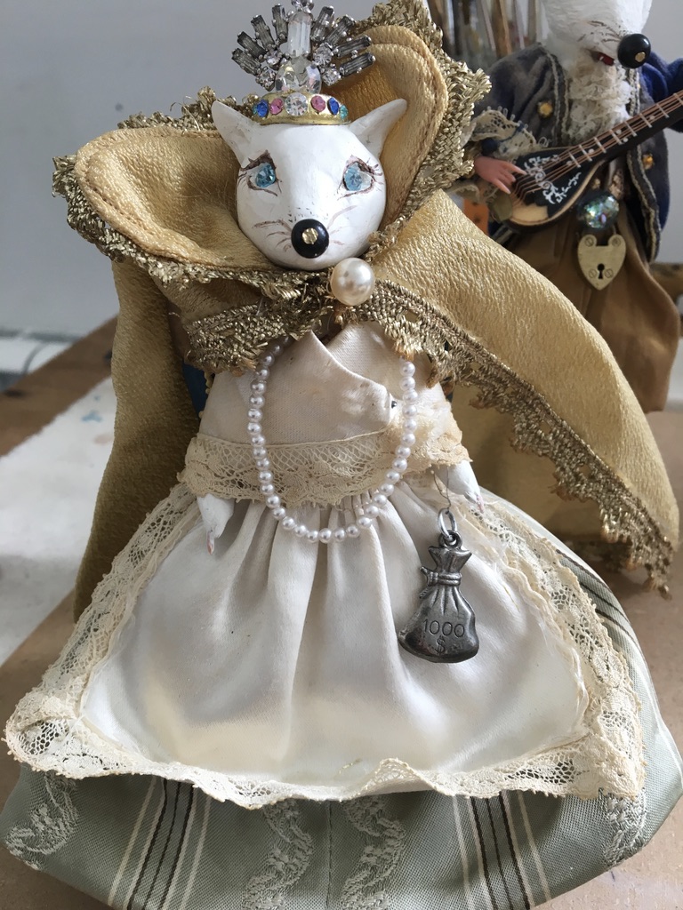 Handmade white fox figure wearing lace, pearls, a gold cloak and a jewelled crown.