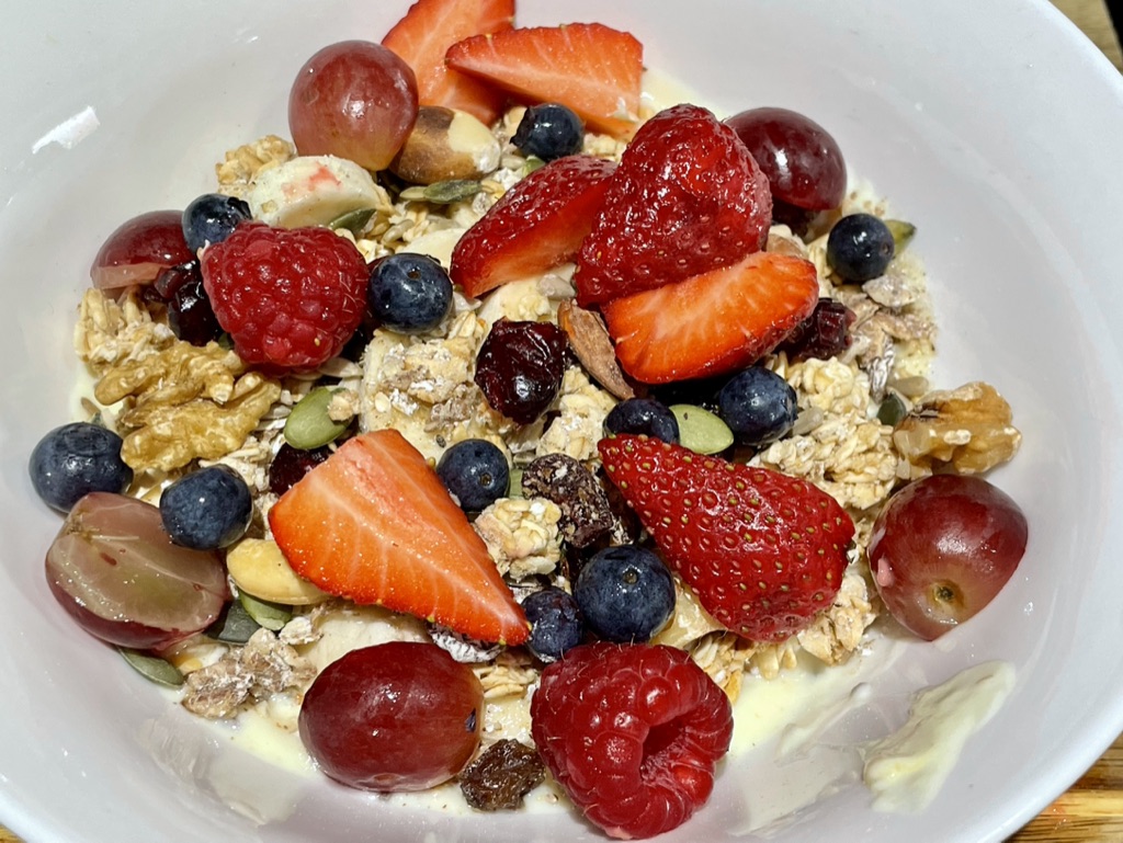 A breakfast bowl of oats, granola, chia seeds, vegan yoghurt and seasonal berries.