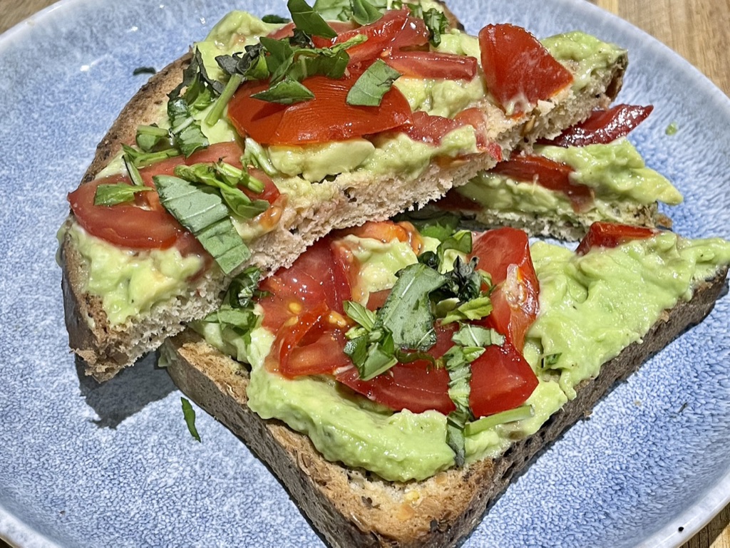 Crushed avocado and vine tomato on toast with fresh basil and lemon juice.