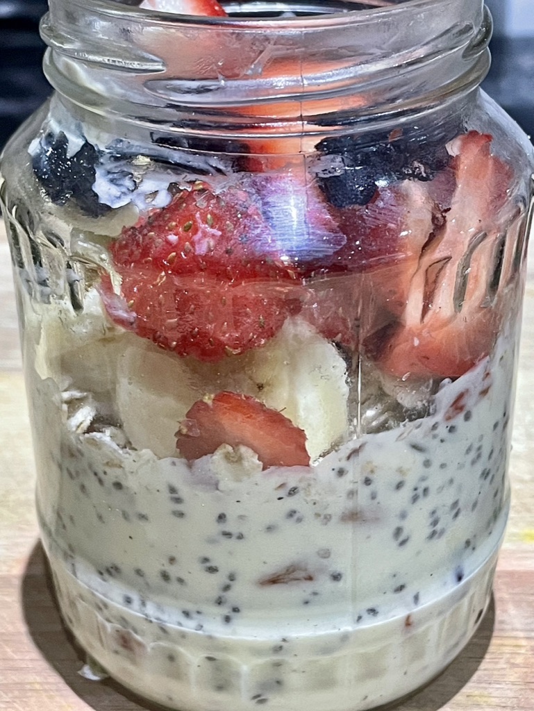 Close-up of a jar of overnight oats with chia seeds, banana, strawberries and berries.