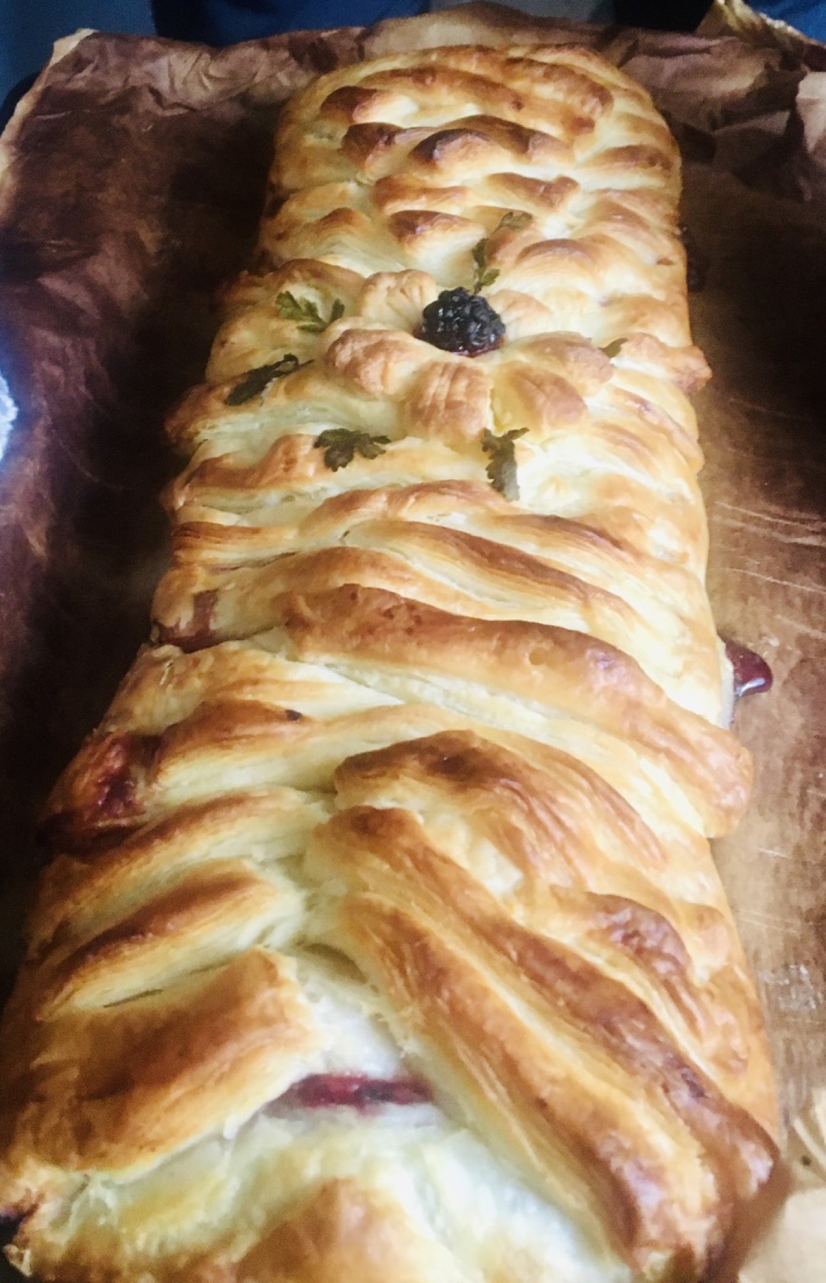 Baked apple and blackberry strudel with golden puff pastry and a blackberry decoration.