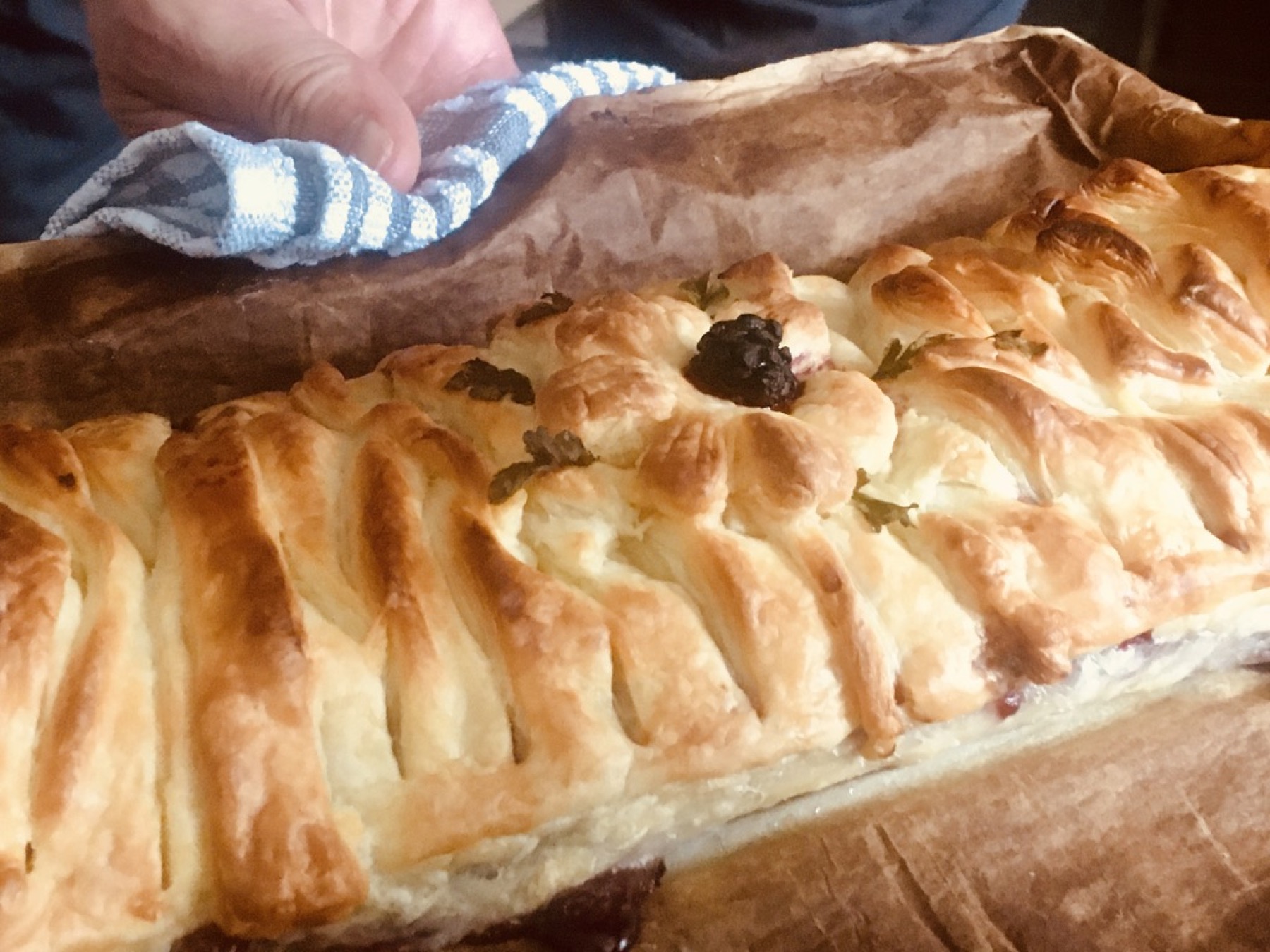 Close-up of baked apple and blackberry strudel on parchment paper.