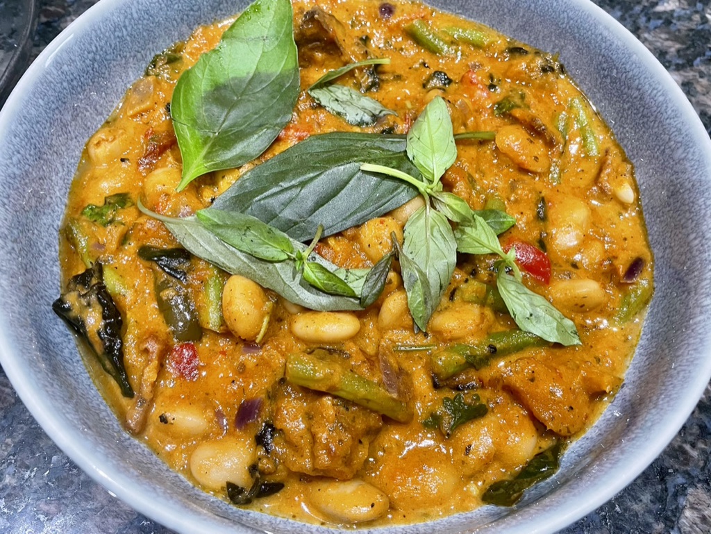 Butter bean coconut curry bowl with green beans, herbs and basil leaves.
