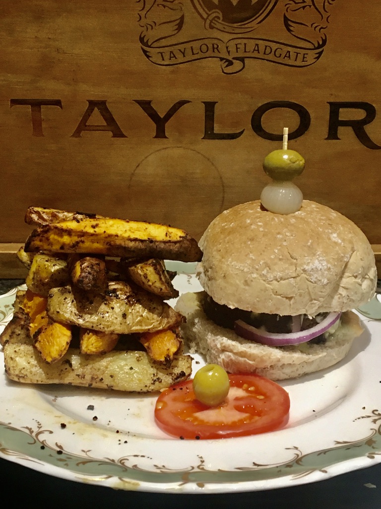 Loaded plant burger served with air-fried sweet potato chips, tomato and olives.