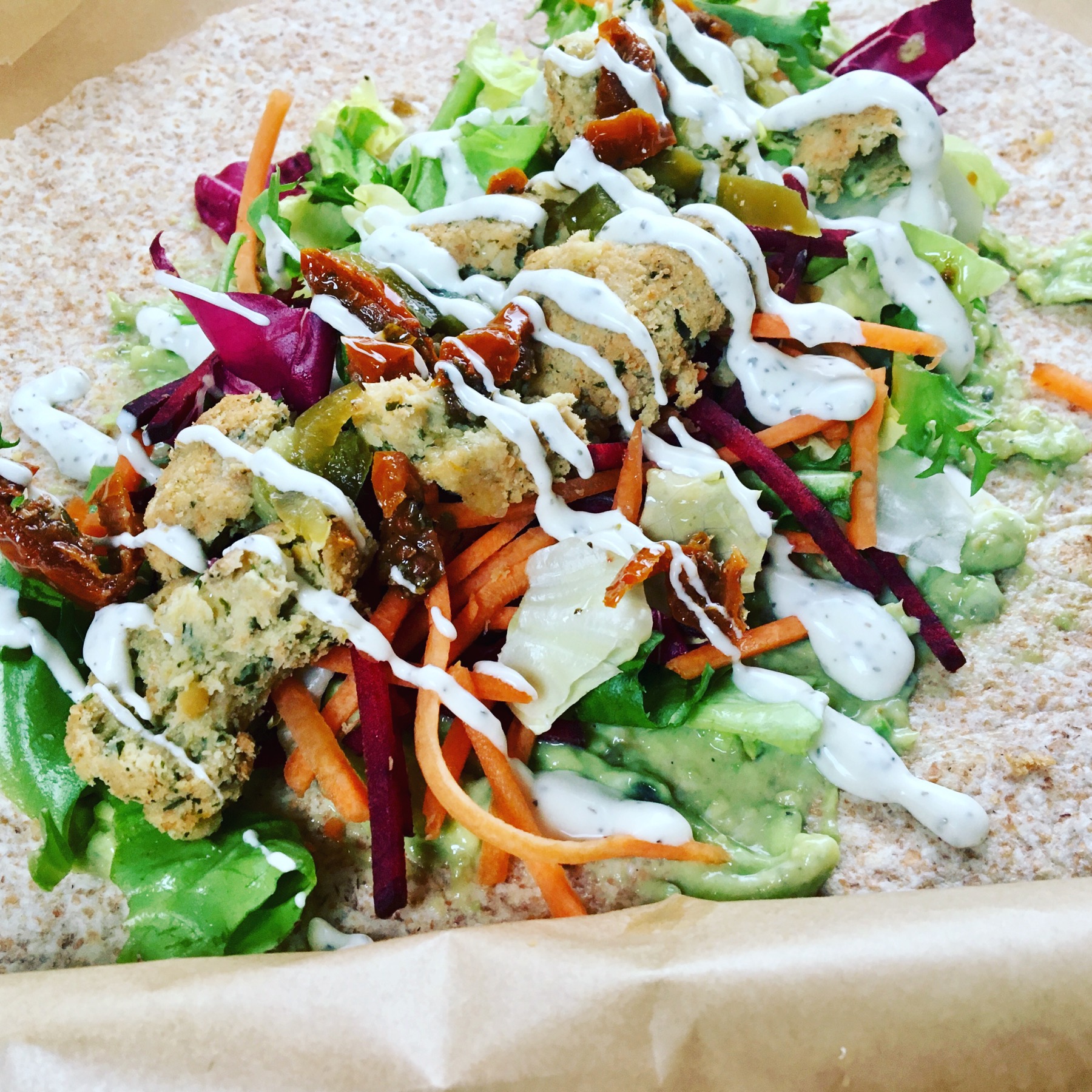 Falafel and avocado wrap with salad, carrot, beetroot, sun-dried tomatoes and dressing.