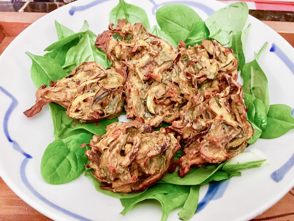 Baked onion bhajis served on spinach leaves.